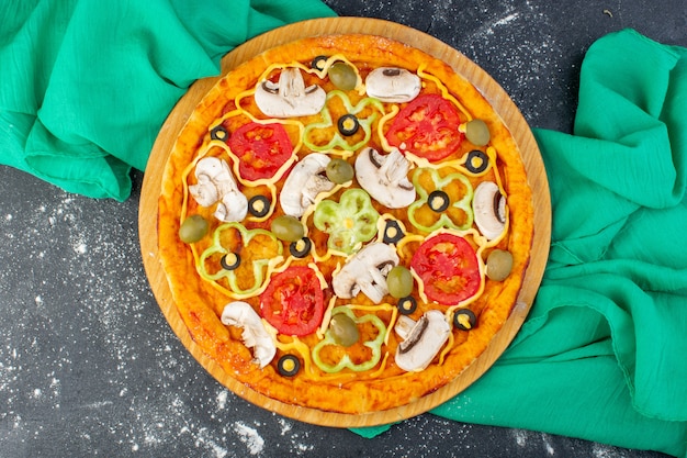 Vista superior de la pizza de champiñones con tomates rojos aceitunas champiñones todos en rodajas por dentro con aceite en el escritorio gris masa de pizza de tejido verde italiano