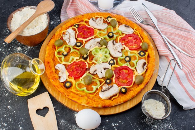 Vista superior pizza de hongos picante con tomates rojos pimientos aceitunas en rodajas por dentro con aceite sobre la masa de pizza de fondo oscuro