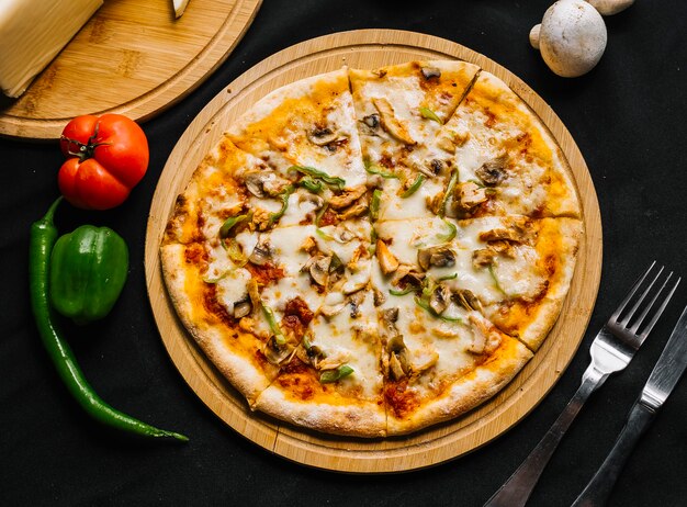 Vista superior de pizza de pollo con pimiento verde, champiñones, queso y salsa de tomate