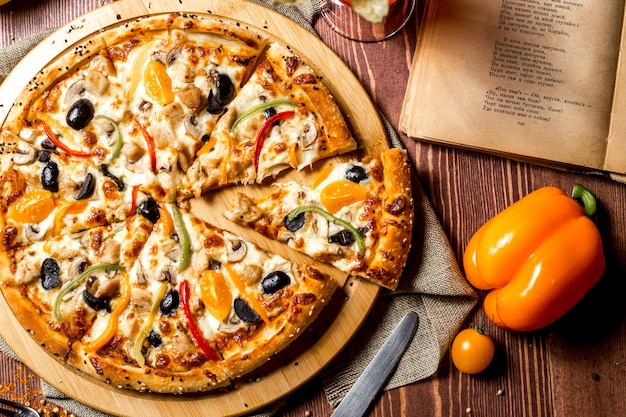 Vista superior de pizza de pollo con tomates cherry amarillos y pimiento en el tablero