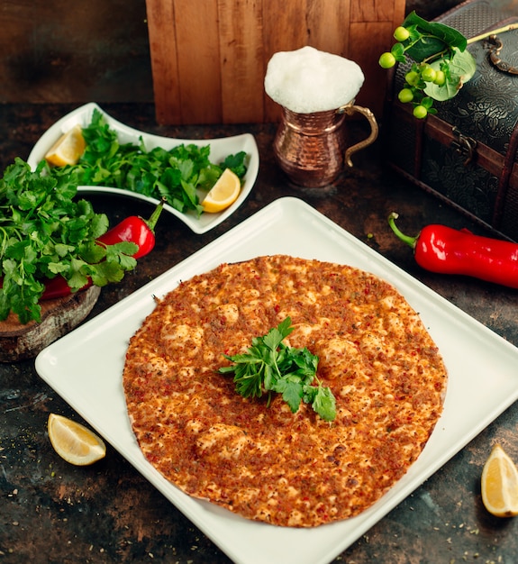 Vista superior de la pizza turca lahmacun servida con perejil, limón y ayran