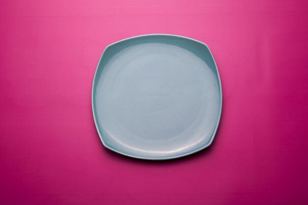 Vista superior de una placa de cerámica aislada sobre una superficie de color rosa brillante
