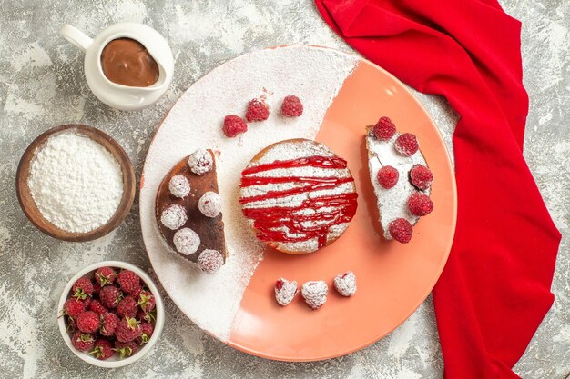 Vista superior de la placa de dulce con harina de bayas tamiz de té y chocolate sobre una servilleta roja en el lado sobre fondo de mármol