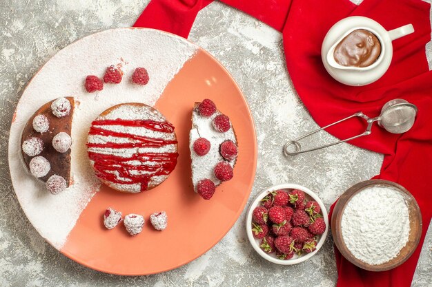 Vista superior de la placa de dulce con harina de bayas tamiz de té y chocolate sobre una servilleta roja en el lado sobre fondo de mármol