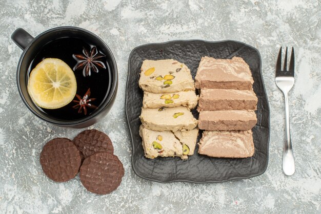 Vista superior de la placa de dulces de semillas de girasol halva tenedor una taza de té galletas