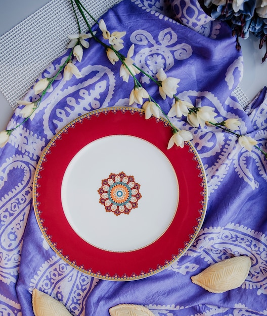 Vista superior de la placa oriental de cerámica con un patrón nacional en la pared de la bufanda femenina de seda tradicional kelagai púrpura