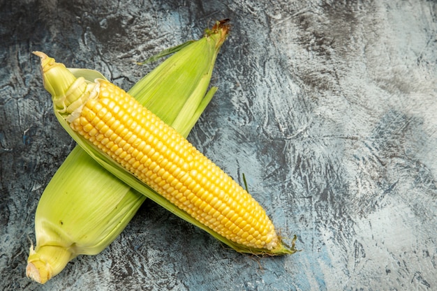 Foto gratuita vista superior de la planta amarilla de maíz crudo fresco en la mesa de luz oscura color verde