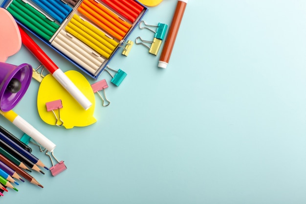 Vista superior plastilinas de colores con lápices de colores en el libro de niños de la escuela de color de pared azul