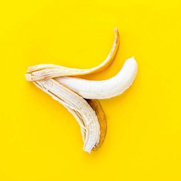 Vista superior de plátano pelado sobre fondo amarillo