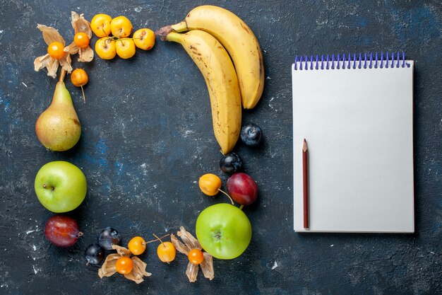 Vista superior de plátanos amarillos con manzanas verdes frescas, peras, ciruelas y cerezas dulces Bloc de notas en el escritorio oscuro.