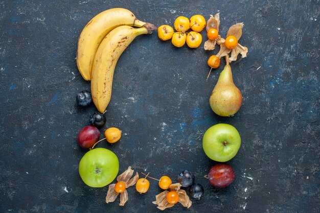 Vista superior de plátanos amarillos con manzanas verdes frescas, peras, ciruelas y cerezas dulces en el escritorio oscuro, salud, vitamina, fruta, baya