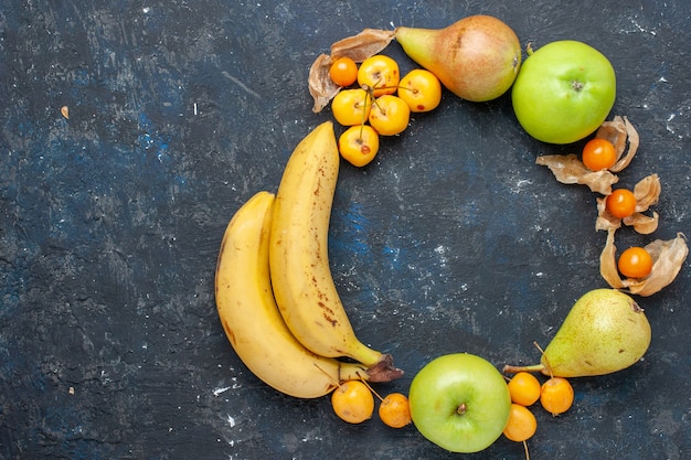 Vista superior de plátanos amarillos par de bayas con manzanas verdes frescas peras cerezas dulces en el escritorio azul oscuro fruta baya salud fresca