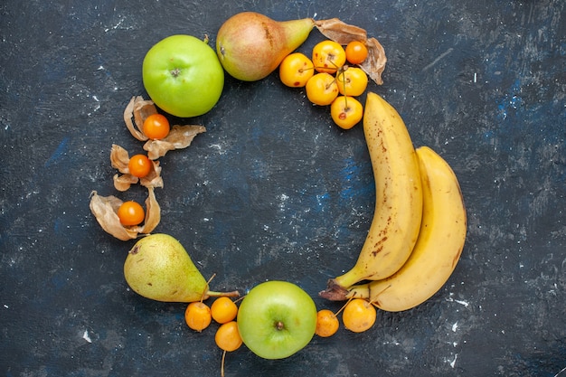 Vista superior de plátanos amarillos par de bayas con manzanas verdes frescas peras cerezas dulces en el piso azul oscuro fruta baya salud fresca