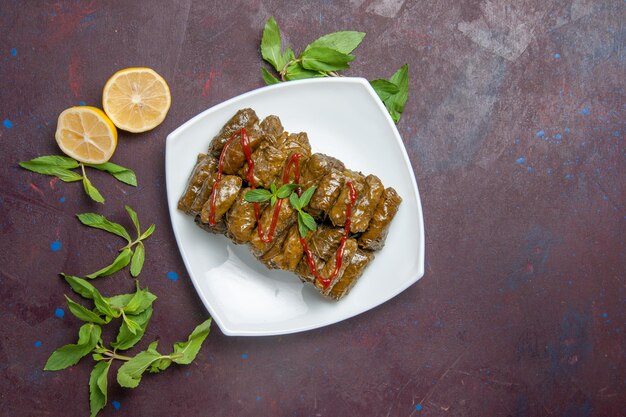 Vista superior del plato de carne molida dolma de hoja deliciosa dentro de la placa en el escritorio oscuro plato de carne comida de cena