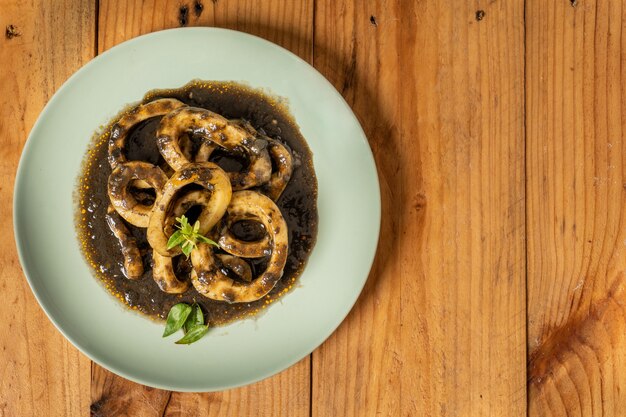 Vista superior de un plato de deliciosos calamares preparados con tinta y salsas