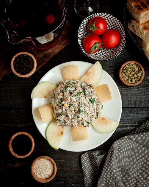 Vista superior del plato de ensalada de manzana con lechuga de maíz, pollo, mayonesa y pasas