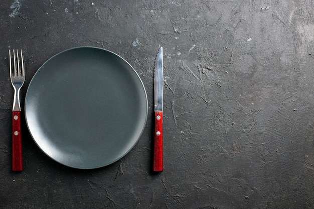 Vista superior plato de ensalada negro tenedor y cuchillo en el espacio de copia de superficie negra