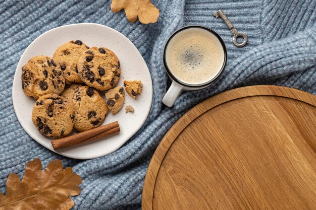 Vista superior del plato de galletas con taza de café y hojas de otoño