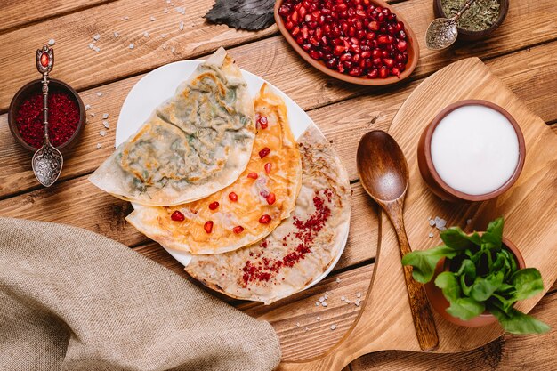 Vista superior de plato de gutabs azerbaiyanos con hierbas calabaza y carne servida con yogurt