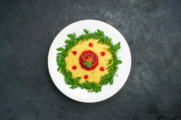 Vista superior del plato de papa triturada con salsa de tomate y verduras en la oscuridad