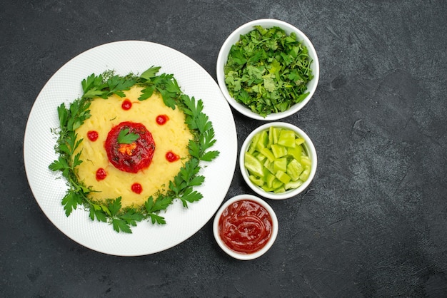 Vista superior del plato de papa triturada con salsa de tomate y verduras en la oscuridad