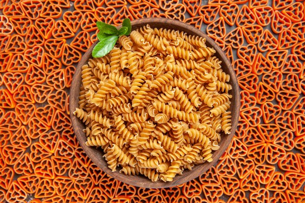 Vista superior de un plato de pasta spirali en pasta italiana en forma de corazón en la mesa oscura