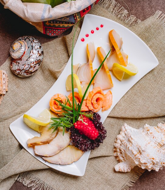 Vista superior plato de pescado ahumado salmón balyk con hierbas granada y rodajas de limón