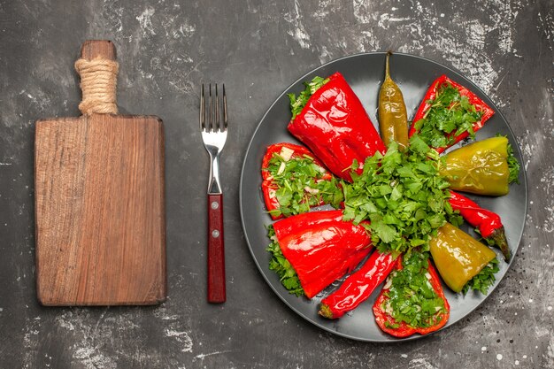 Vista superior del plato de pimientos pimientos con hierbas en el plato horquilla la tabla de cortar