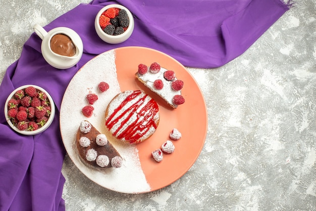Vista superior del plato de postre en una servilleta morada con bayas y chocolate en el lateral sobre fondo de mármol