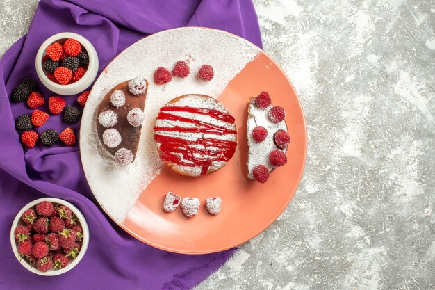 Vista superior del plato de postre en una servilleta morada con bayas en el lado sobre fondo de mármol