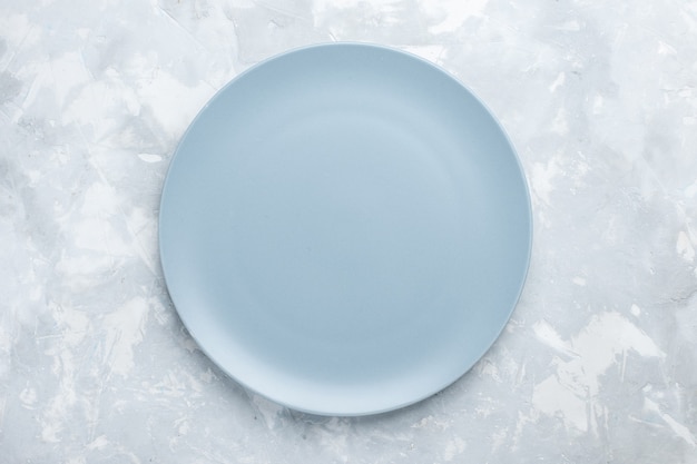 Vista superior plato redondo vacío de color azul hielo en el plato de escritorio blanco cubiertos cocina comida