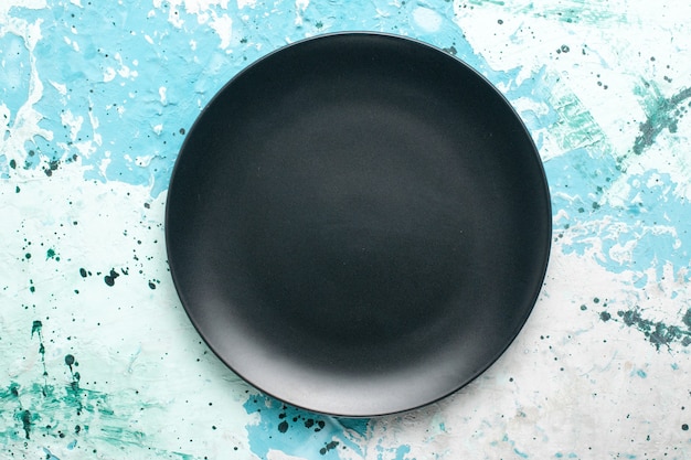Vista superior plato redondo vacío de color oscuro sobre el fondo azul plato de color cubiertos de cocina de vidrio