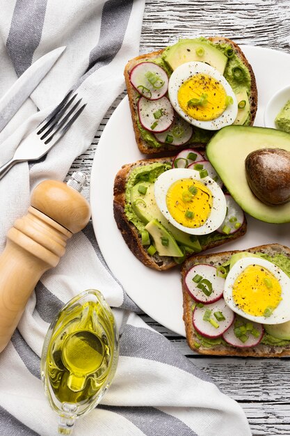 Vista superior del plato con sándwiches de huevo y aguacate y cubiertos