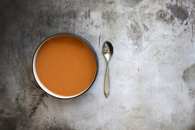 Vista superior de un plato de sopa con una cuchara sobre la mesa bajo las luces