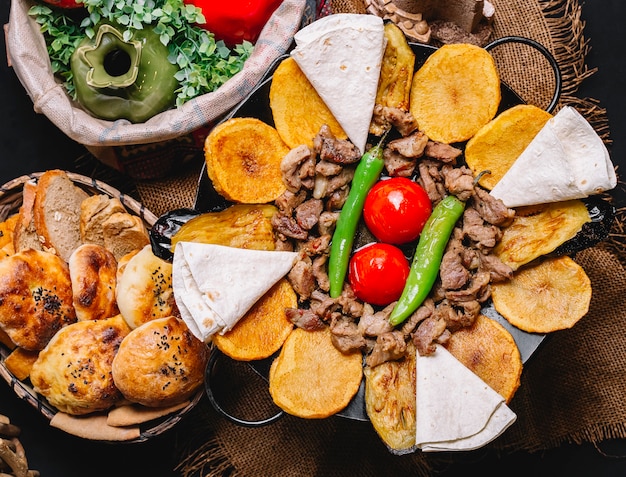 Vista superior de un plato tradicional azerbaiyano salvia de carne con pan de pita, papas, tomates y pimiento verde