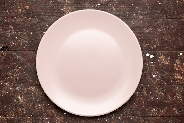 Vista superior del plato vacío rosado en placa de madera rústica marrón, madera