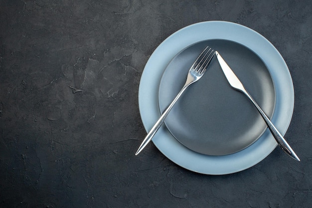 Vista superior platos elegantes con cuchillo y tenedor sobre fondo oscuro hambre cubiertos feminidad cena colorida