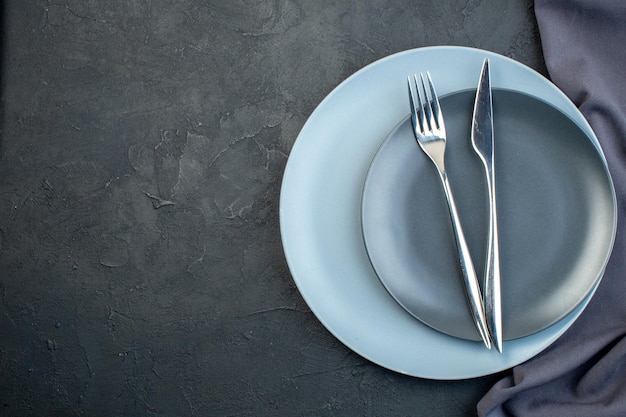 Vista superior platos elegantes con tenedor y cuchillo sobre fondo oscuro cubiertos feminidad cena hambre colorido