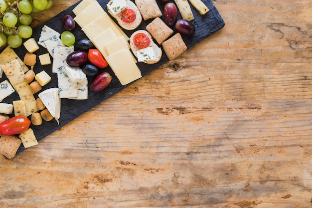 Vista superior de platos de queso con uvas y tomates en mesa