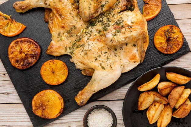 Vista superior de pollo al horno con rodajas de naranja y gajos