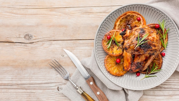 Vista superior de pollo al horno y rodajas de naranja en un plato con espacio de copia