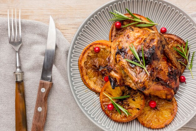 Vista superior de pollo al horno y rodajas de naranja en un plato