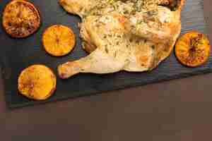 Foto gratuita vista superior de pollo al horno en tabla de cortar con rodajas de naranja