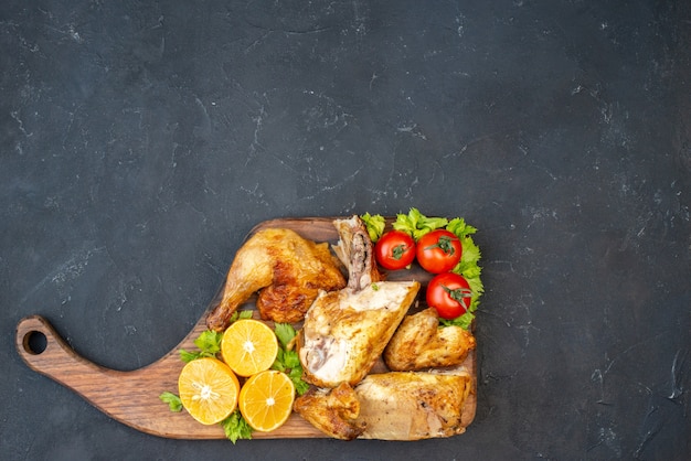 Vista superior de pollo al horno tomates rodajas de limón sobre tabla de madera