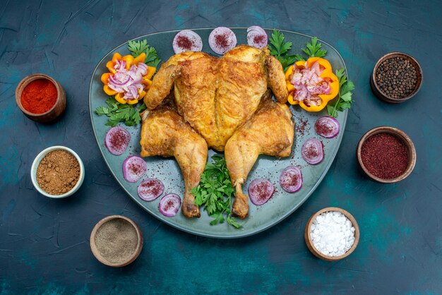 Vista superior pollo cocido con cebollas y verduras dentro de la placa en el escritorio azul oscuro carne de pollo hornear cena en horno