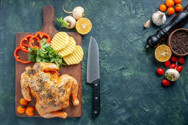 Vista superior de pollo cocido condimentado con patatas en la superficie oscura