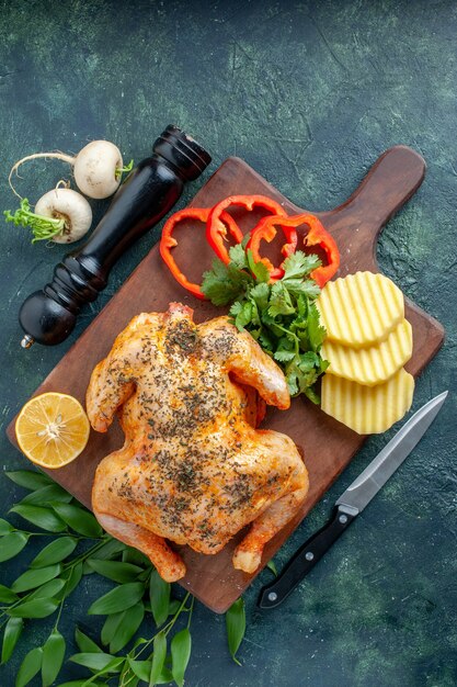 Vista superior de pollo cocido condimentado con patatas en la superficie oscura