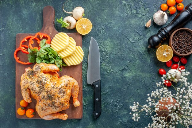 Vista superior de pollo cocido condimentado con patatas en la superficie oscura