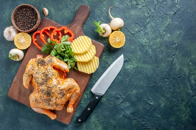 Vista superior de pollo cocido condimentado con patatas en la superficie oscura