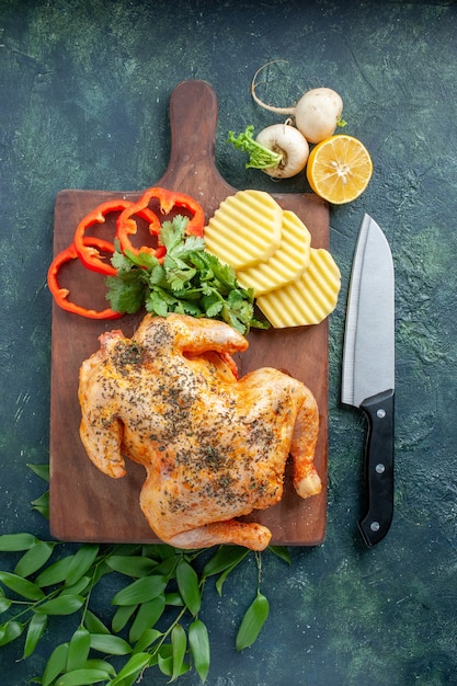 Vista superior de pollo cocido condimentado con patatas en la superficie oscura